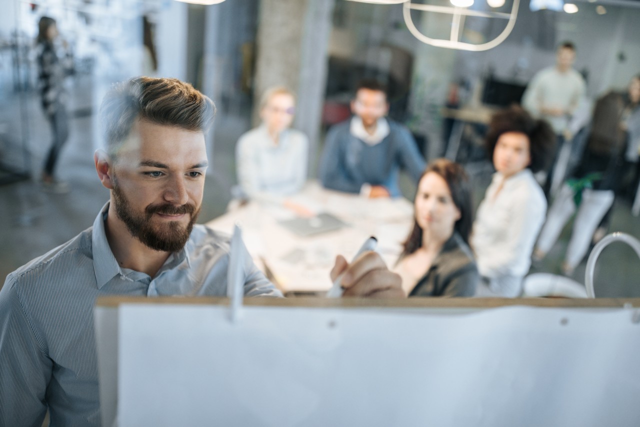 collega's aan het werk, met een collega die voor de groep staat en uitkomsten op een flip over noteert.