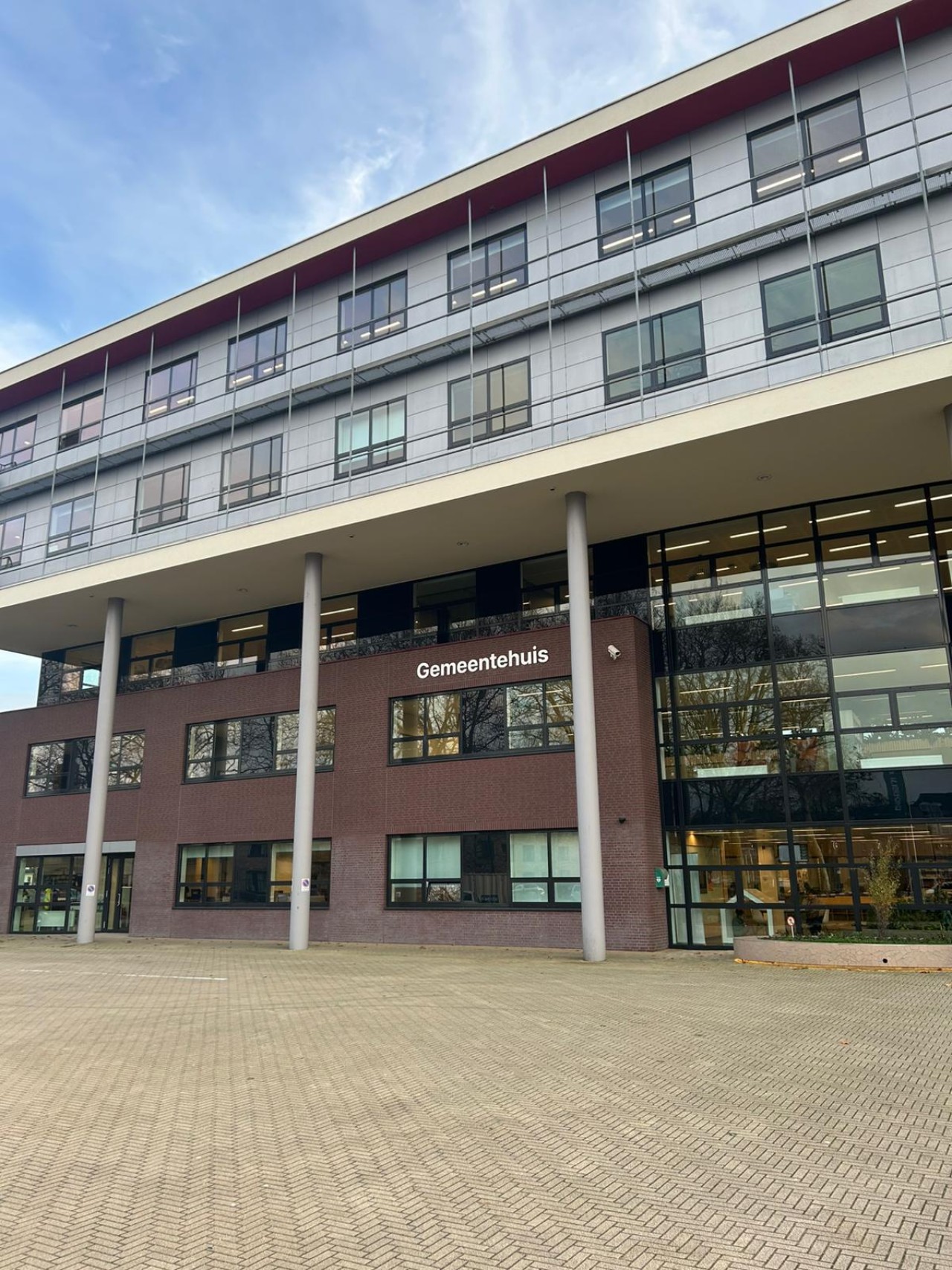 Een gemeentehuis met drie smalle witte palen aan de voorkant.