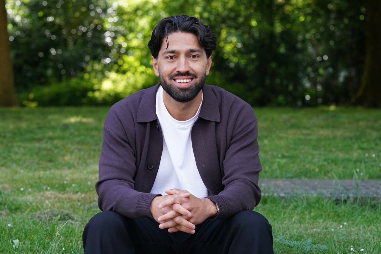 Hamed Amir poseert zittend in een park
