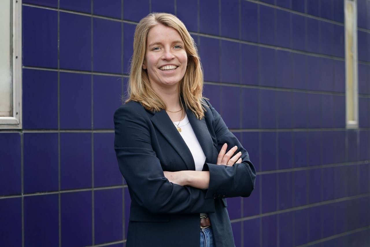 Janne Peters poseert bij een blauwe tegelmuur voor haar portret