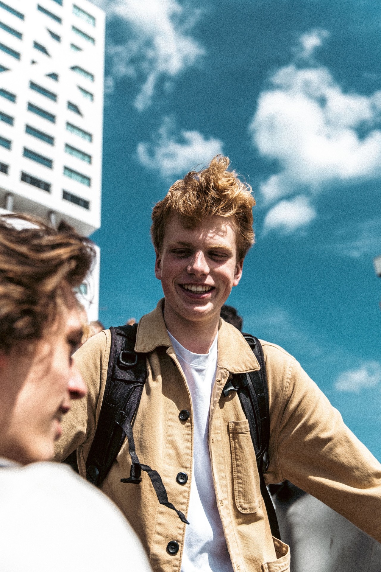 Twee jongeren staan buiten op een zonnige dag en lachen