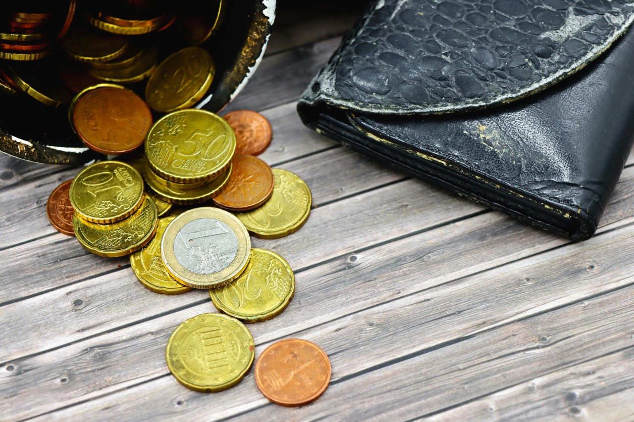 Een portemonnee met daarnaast een aantal euromunten op een tafeletje.