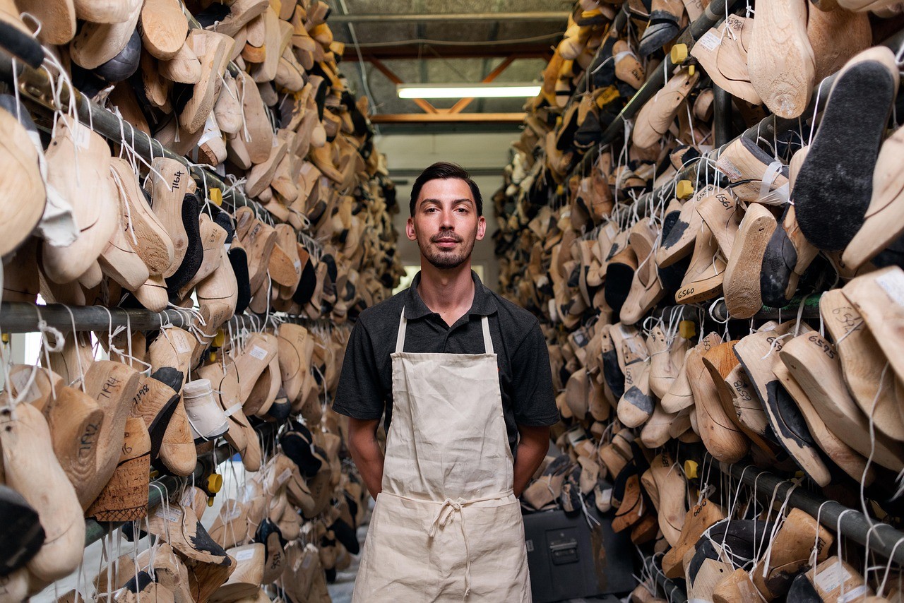 Man poseert bij rijen met mallen van schoenen