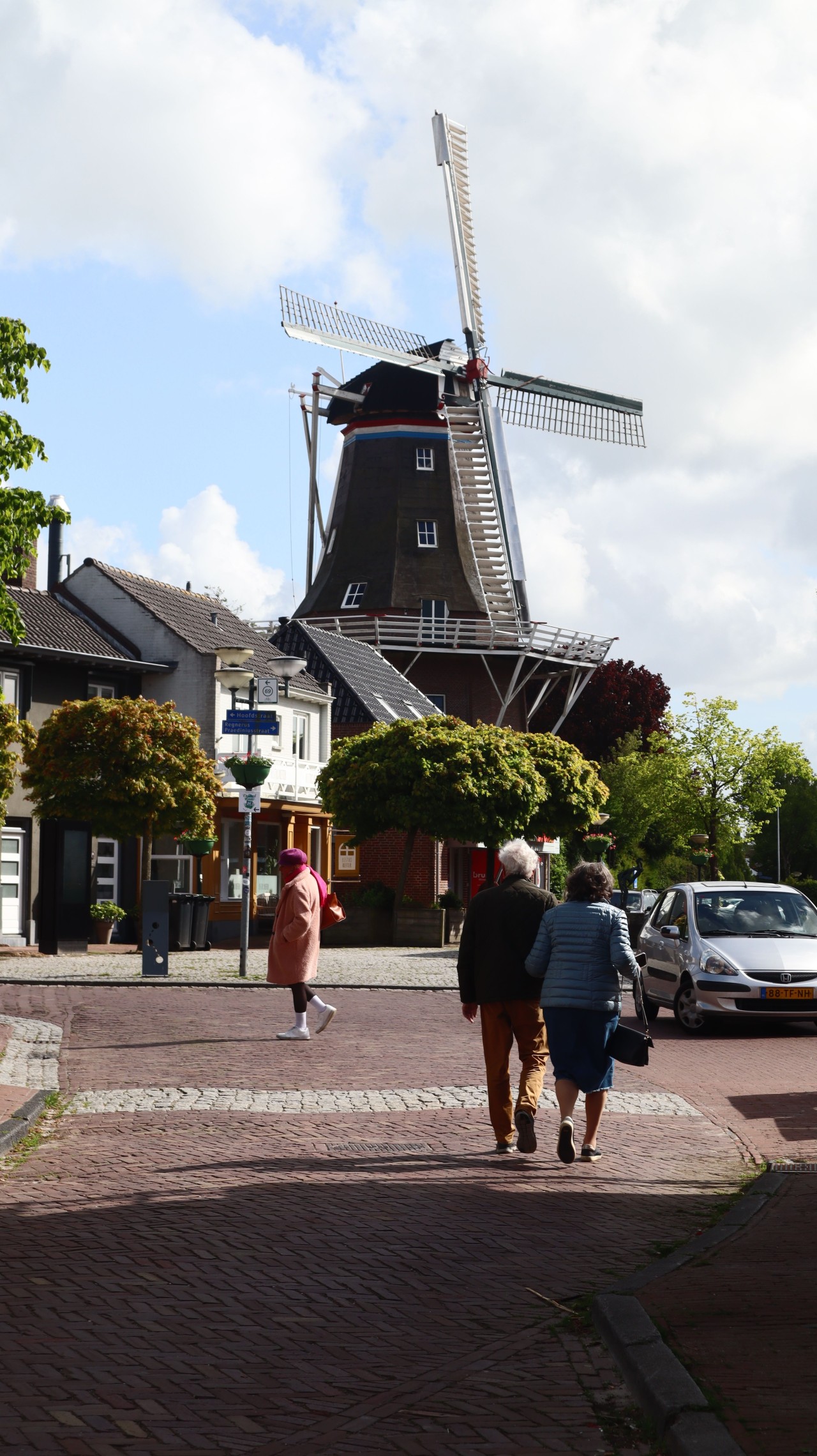 Mensen wandelend door de stad met op de achtergrond een molen