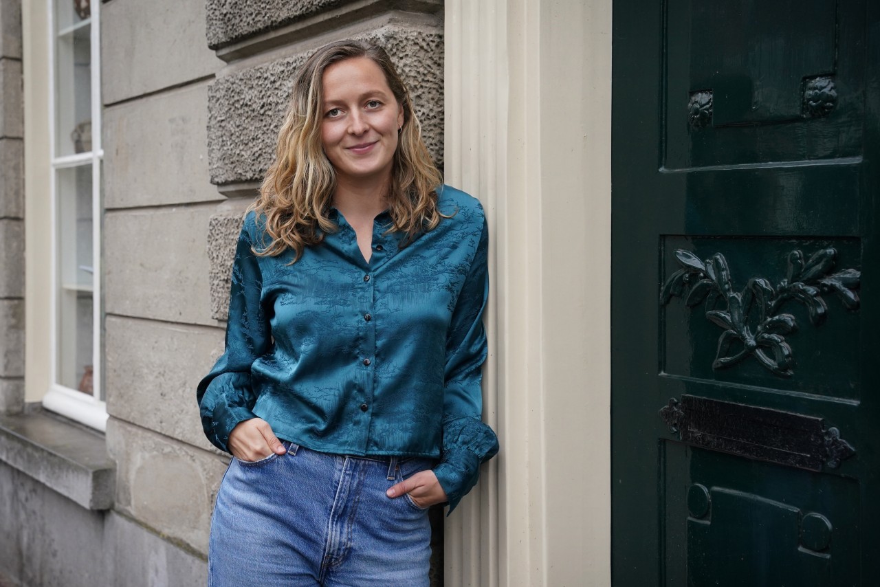 Nina van Rossem poseert voor haar portretfoto leunend tegen een deurstijl