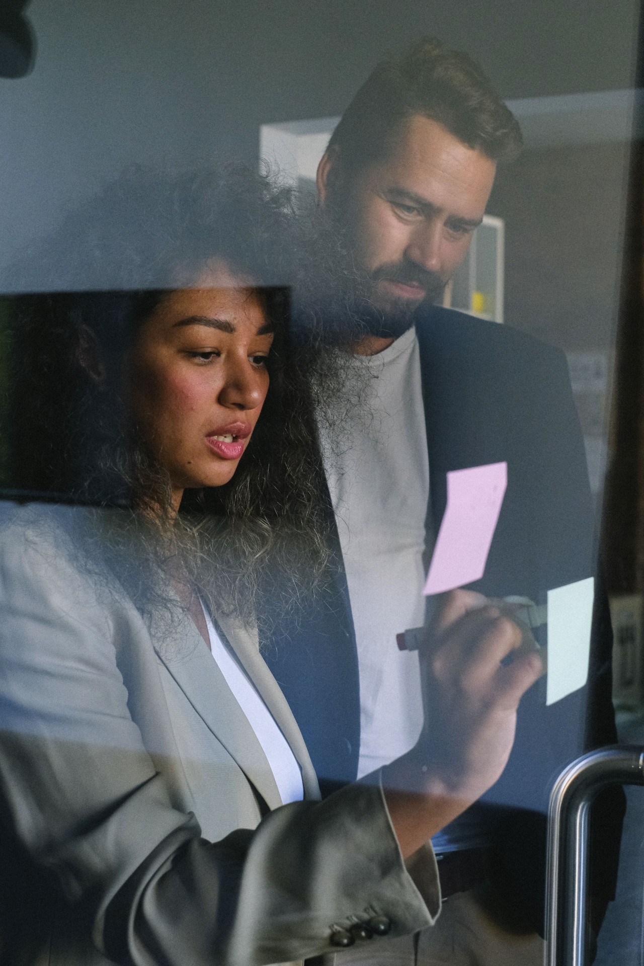 Twee collega's werken samen bij een glazen wand